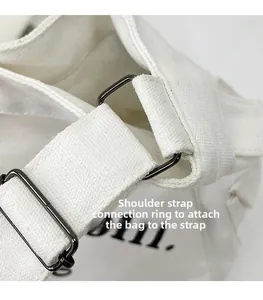 Détail de la boucle en métal foncé sur le sac cabas en toile blanche avec coutures renforcées