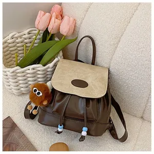 Fashionable brown and beige patchwork backpack with a cute plush monster keychain
