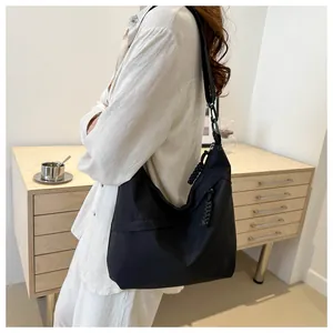 Detail of black tote bag featuring a woven zipper pull and adjustable wide shoulder strap