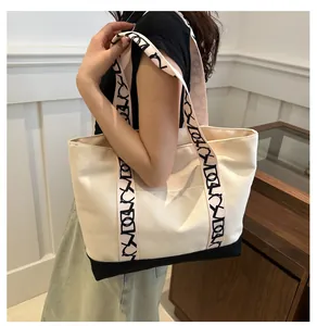 Détail du sac cabas en toile beige avec surpiqûres noires et bandoulière à motifs