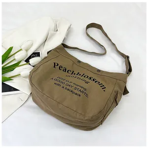 Détail du sac cabas en toile beige avec imprimé lettres noires et bandoulière réglable