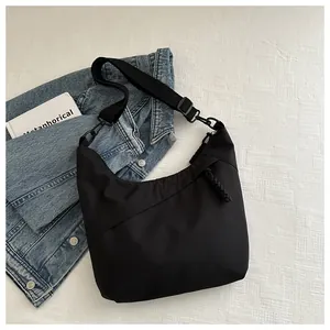 Detail of black nylon crescent tote bag featuring diagonal stitching and adjustable strap