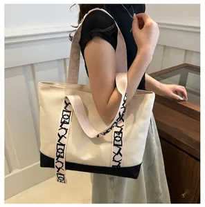 Détail du sac cabas en toile avec fond noir contrasté et bandoulière géométrique