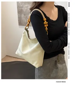 Detail view of cream tote bag with unique round wooden bead handle on female model