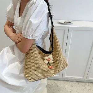 Bolso tote de paja tejido a mano con correas de cuero negro y colgante de flores
