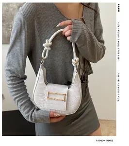 Detail of white crocodile texture handbag with woven rope handle and golden wavy buckle