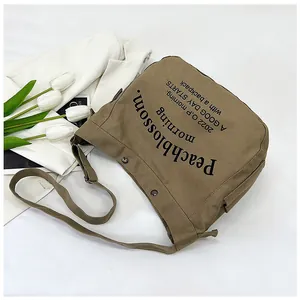 Détail du sac cabas en toile kaki avec lettrage noir et boucle de bandoulière réglable