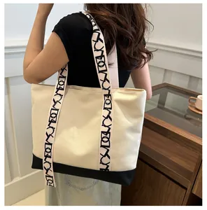 Détail latéral d'un sac cabas en toile minimaliste avec base et bandoulière contrastées