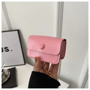 Detail of pink mini chain crossbody bag held in hand showing smooth faux leather texture