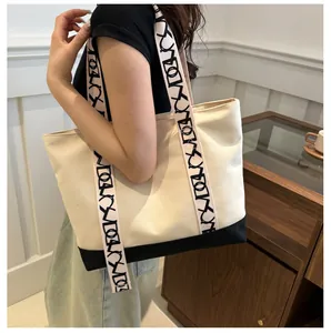 Détail du sac cabas en toile avec base noire et bandoulières à motifs porté par un mannequin