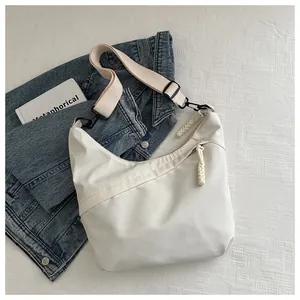 Detail view of cream crescent crossbody bag with adjustable wide strap and zip texture