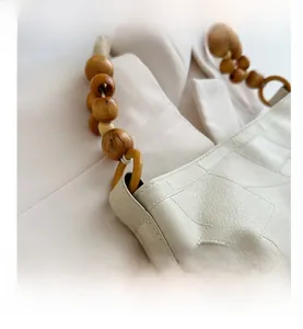 Detailed close-up of off-white lychee grain leather tote with beaded wooden shoulder strap
