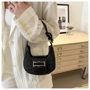 Detail of black crocodile texture shoulder bag with gold clasp and knotted strap