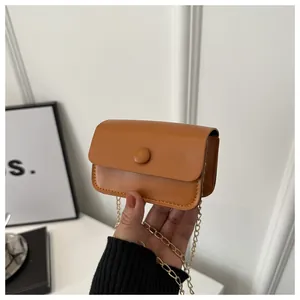 Detail of a mini orange crossbody bag with matte texture and golden chain strap