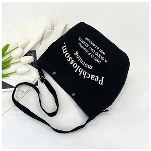 Détail du sac cabas en toile noire avec bandoulière réglable et lettrage artistique