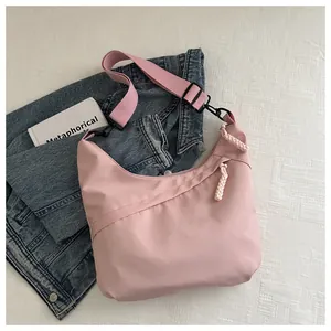 Detail view of pink nylon crescent bag with wide fabric strap and woven zipper pull