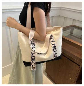 Détail du cabas en toile avec base noire contrastée et bandoulières à motifs géométriques
