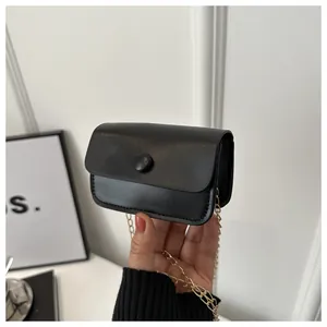 Close-up of black matte PU leather mini coin purse with gold chain strap in hand