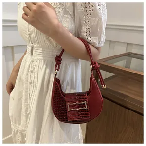 Deep red crocodile embossed crescent bag with gold buckle shown on a model