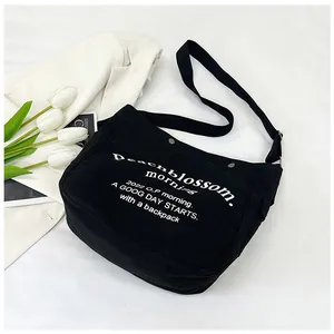 Vue détaillée du sac cabas en toile noire avec typographie blanche et bandoulière réglable