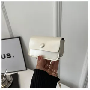 Mini cream chain crossbody bag held in hand showing compact size and textured PU leather