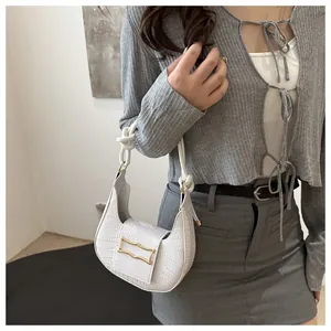 Detail of white hobo bag with crocodile texture and braided rope handle on a model
