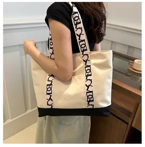 Détail du sac cabas en toile beige avec lettres imprimées sur les bandoulières en gros plan
