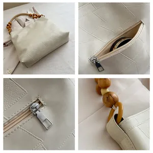 Detail view of cream tote bag with wooden bead handle and geometric stitching texture