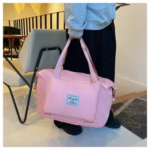 Detail of pink waterproof travel bag showing front zipper pocket and reinforced handles