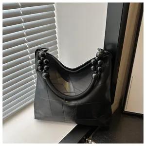 Detail of black large capacity hobo bag with unique bead handle and geometric texture