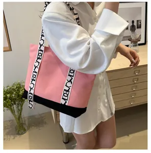 Détail du cabas en toile rose avec larges bandoulières à motifs géométriques noirs