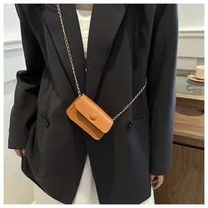 Detail shot of a mini brown leather crossbody bag with a delicate gold chain strap
