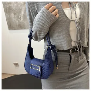 Close-up of deep blue crocodile pattern handbag with unique double knot shoulder strap