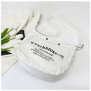Détail du sac cabas en toile blanche avec lettrage noir et boutons métalliques de qualité
