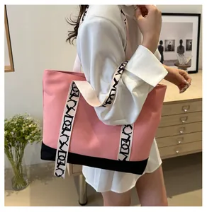 Sac cabas en toile rose avec bandoulière à motifs porté par un mannequin en intérieur