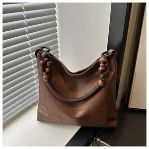 Close-up of vintage brown tote bag with woven handles and large decorative wooden beads