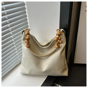 Chic cream tote bag featuring distinctive wooden bead handles in a minimalist indoor setting