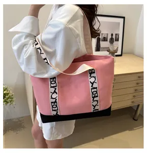 Sac cabas en toile rose avec bordure noire et bandoulière à motifs de lettres décoratives