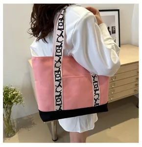 Détail du cabas en toile rose et noir montrant la bandoulière longue avec des motifs