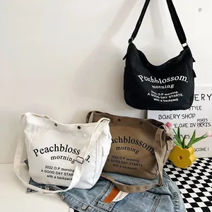 Vue détaillée de sacs fourre-tout en toile noir, blanc et kaki avec sangle réglable