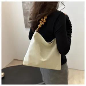 Detail of hobo tote bag featuring large wooden bead strap and creamy soft faux leather