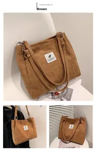 Detail showing brown corduroy tote bag texture with minimalist white label and long strap