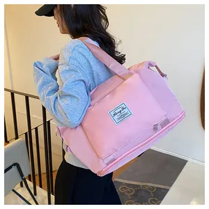 Close-up of pink foldable travel bag with reinforced straps and logo detail