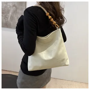 Detail of cream oversized tote bag with geometric stitching and wooden bead handle
