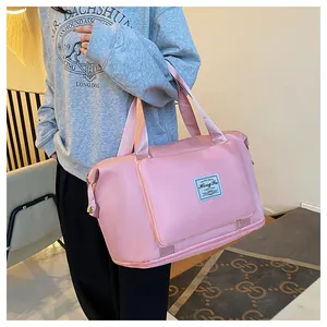 Pink nylon travel bag detail featuring front zipper pocket and reinforced handles