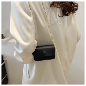 Detail view of minimalist black chain crossbody bag on a silk white suit jacket