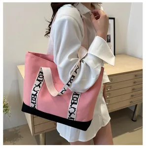 Détail du sac cabas en toile rose avec fond noir et sangles à lettres stylées