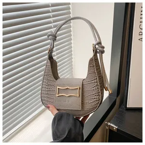 Detail of grey crocodile texture bag featuring a unique knotted handle and gold buckle