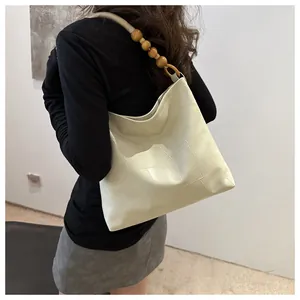 Detail of off-white tote bag with unique patchwork texture and wooden bead strap