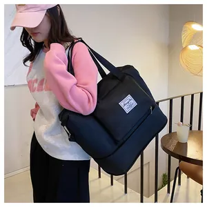 Large black travel duffel bag with shoulder straps and expandability shown on a model